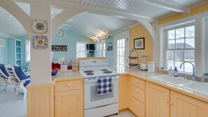 A kitchen with a white stove, wooden cabinets, and a large window. - Cozy 'Fiddler's Rest:' Cabin: 11 Miles to Skiing! (Vernon)