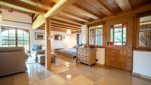 A spacious room with a wooden ceiling, a bed, a dresser, and a window with a view of greenery. - Maisonette apartment for 4 people, 95 sqm with terrace (Obing)
