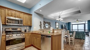 A kitchen with wooden cabinets, stainless steel appliances, a dishwasher, and a dining area with a table and chairs.