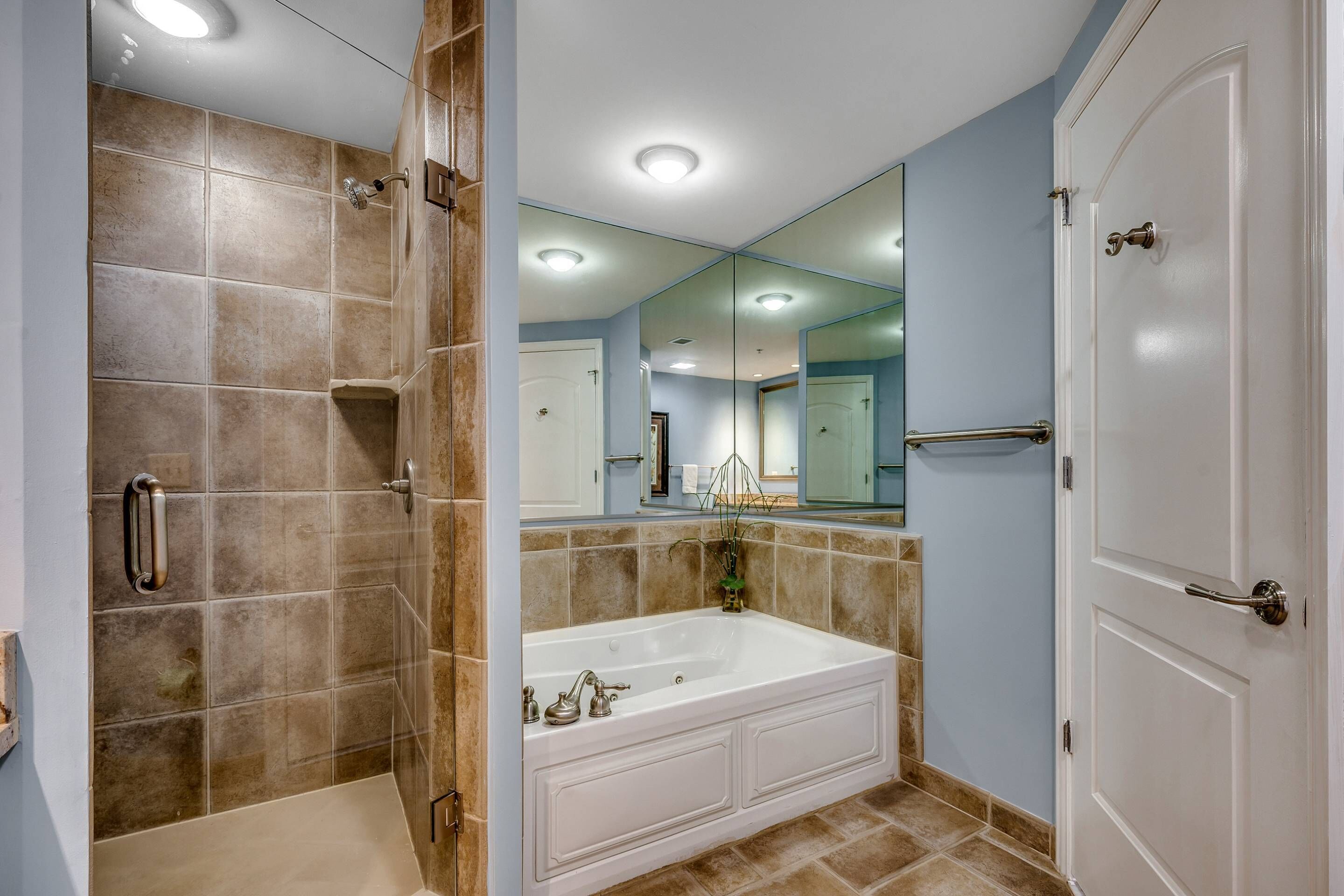 A bathroom with a bathtub, shower, and a large mirror.