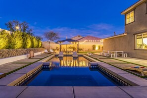 Ein Garten mit Swimmingpool, Liegestühlen und einer Terrassenfläche.