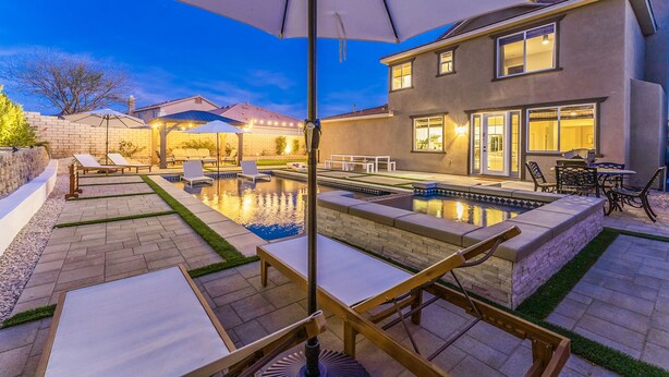 Ein Garten mit Schwimmbad, Terrassenmöbeln und einer überdachten Sitzgelegenheit.