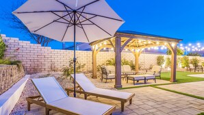 Eine Terrasse mit Lounge-Möbeln, eine Pergola mit Lichterketten und eine Backsteinmauer im Hintergrund.