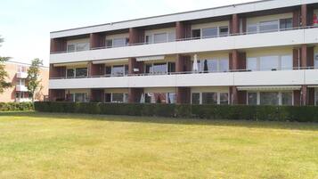 Ein mehrgeschossiges Gebäude mit Flachdach, rechteckigen Fenstern und einem Balkon im oberen Stockwerk.
