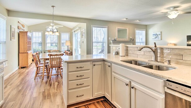 A modern kitchen with white cabinetry, a built-in dishwasher, and a large island with seating. - 3 Mi to Coast: Pool & Serene Pond Views (Ocean View)