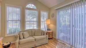 A living room with a checkered sofa, three windows with blinds, a lamp, and a small side table with a sign. - 3 Mi to Coast: Pool & Serene Pond Views (Ocean View)