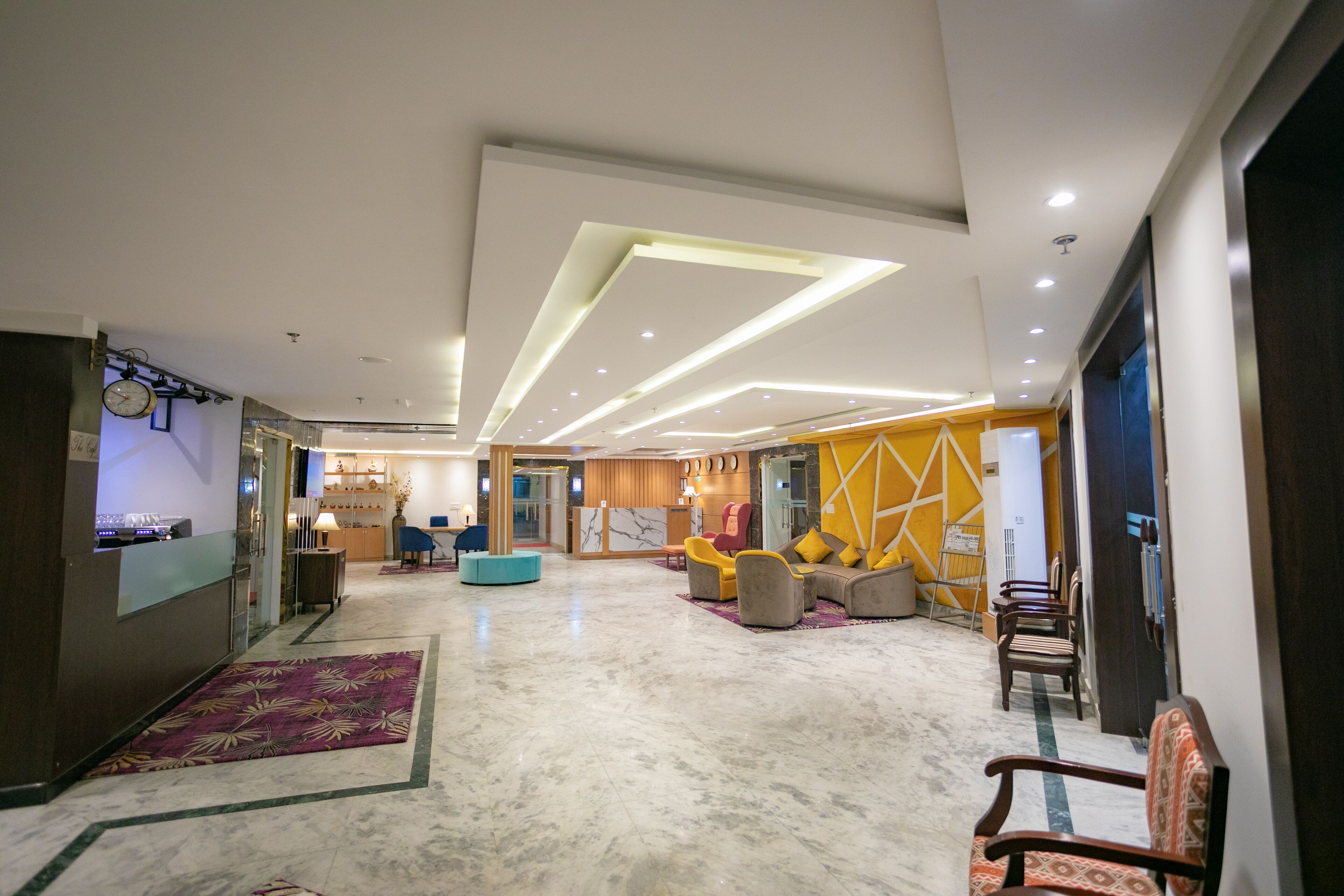 A spacious lobby with a reception desk, seating area, and a modern ceiling design.