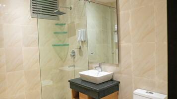 A modern bathroom with a glass-enclosed shower, a sink with a mirror above, and a toilet.