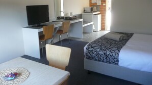 Une chambre d’hôtel équipée d’un lit, d’un bureau avec un ordinateur, d’une télévision et d’un four à micro-ondes.