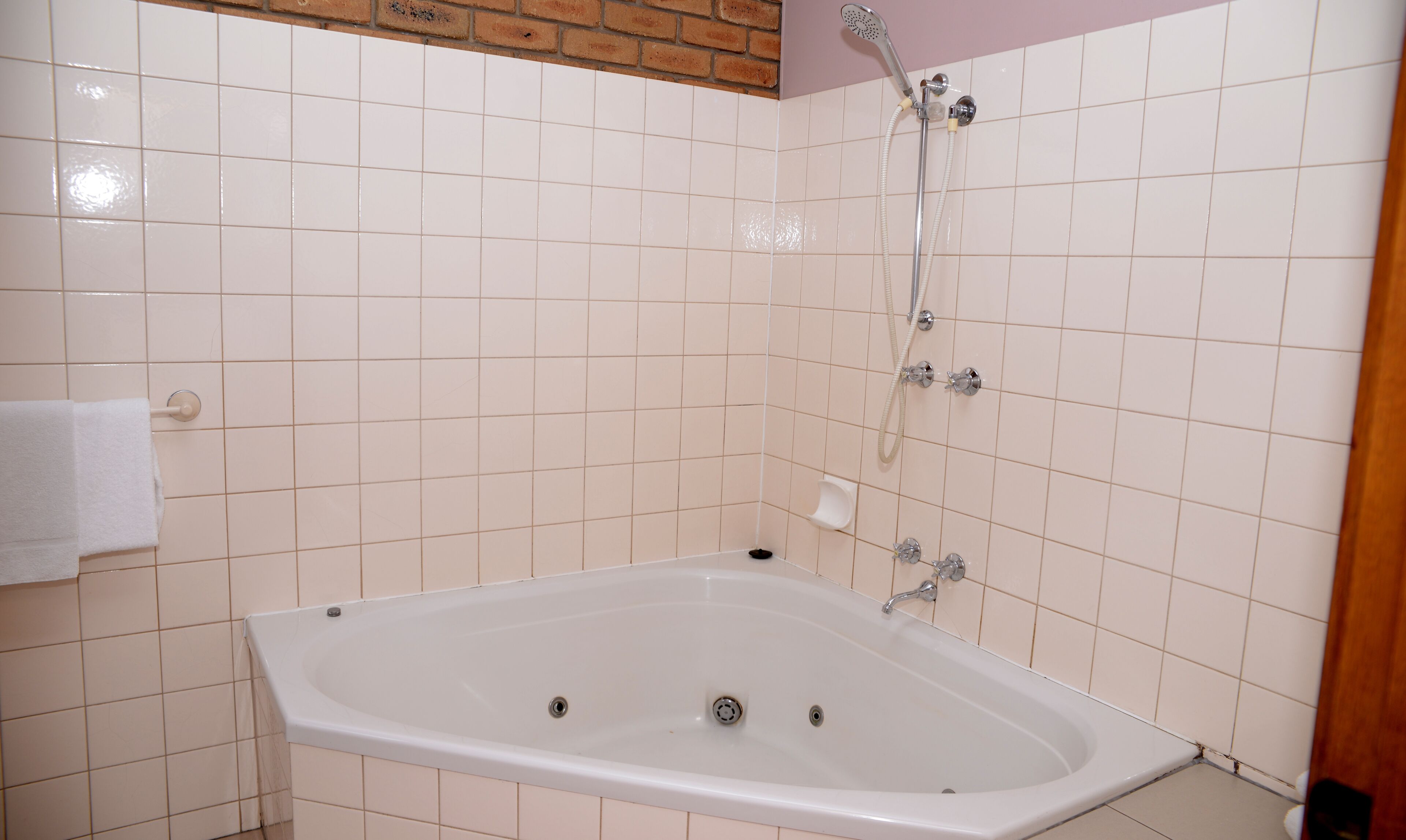 A bathroom with a white bathtub, a showerhead, and a towel rack.