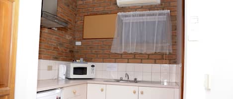 Una cocina funcional con microondas, fregadero y pared de ladrillo.