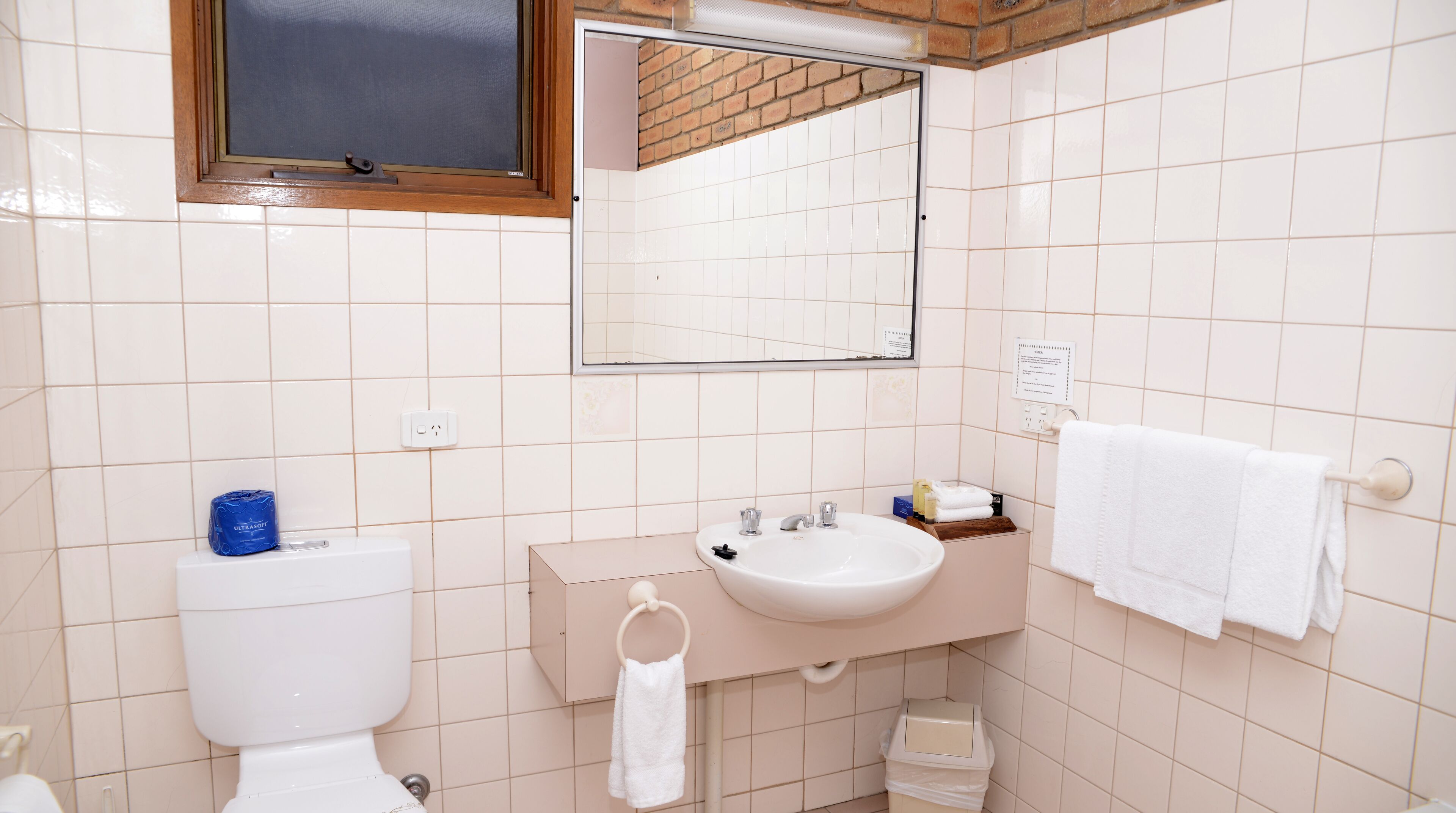 Un baño con inodoro, lavabo, espejo y toallero.