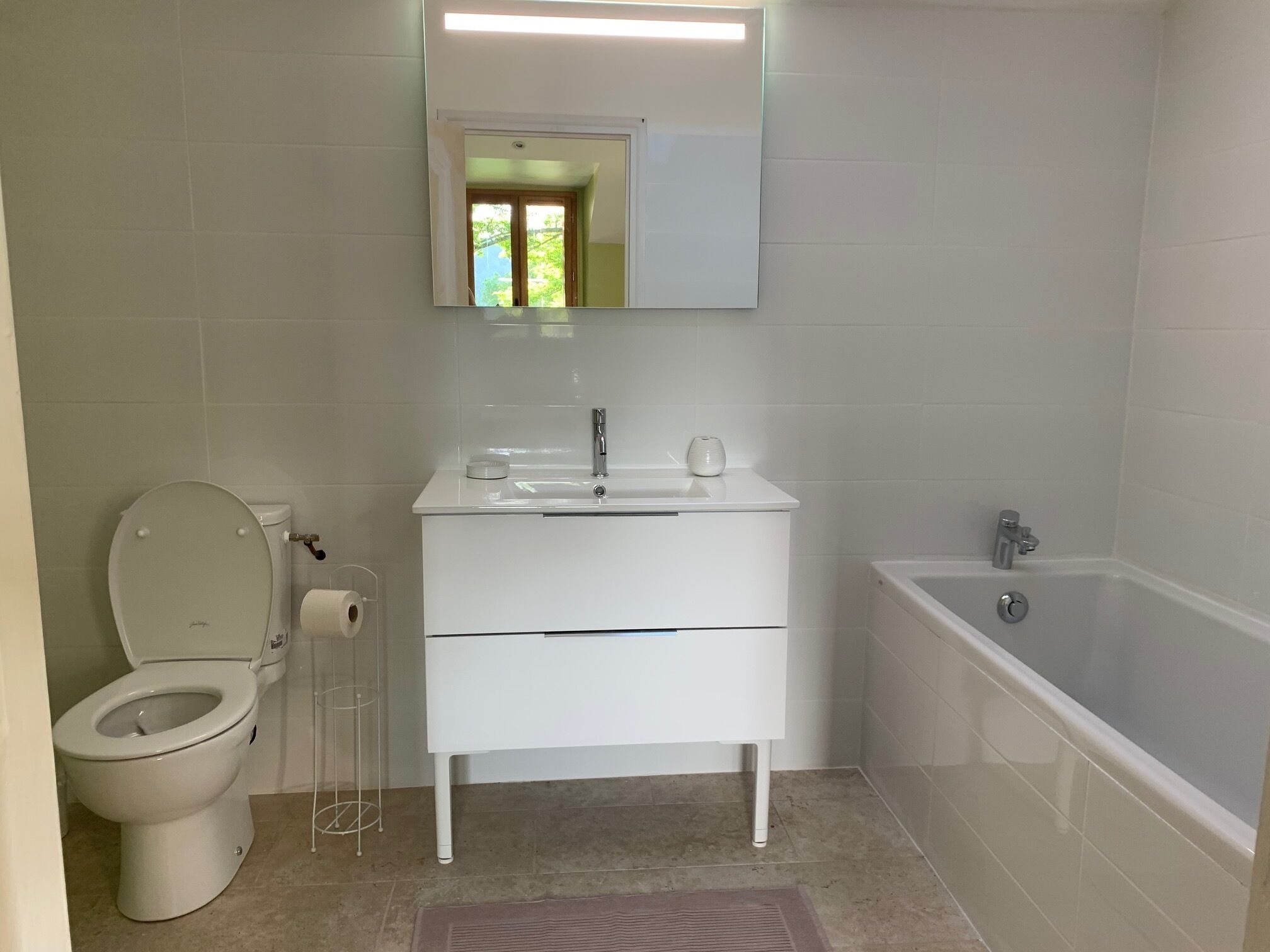 A modern bathroom with a toilet, sink, and bathtub.