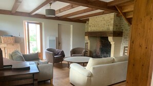 Un salon chaleureux avec une cheminée, des poutres en bois et des sièges confortables.