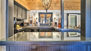 A modern kitchen with a central island, wooden ceiling, and stainless steel appliances. - Eclectic 'Osage Cottage' in Historic District (Eureka Springs)