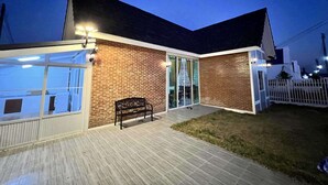 A modern building with a brick facade, large glass windows, and a wooden deck. - Homerent @ Sariam Lake Chiang Mai (San Pa Thong)