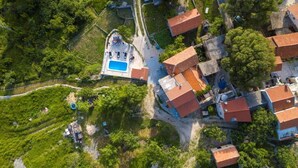 Luchtbeeld van een woongebied met huizen, een zwembad en omliggend groen.