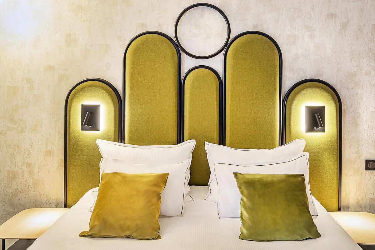 Ein Hotelzimmer mit einem modernen Kopfteil, zwei Nachttischen und zwei Kissen.