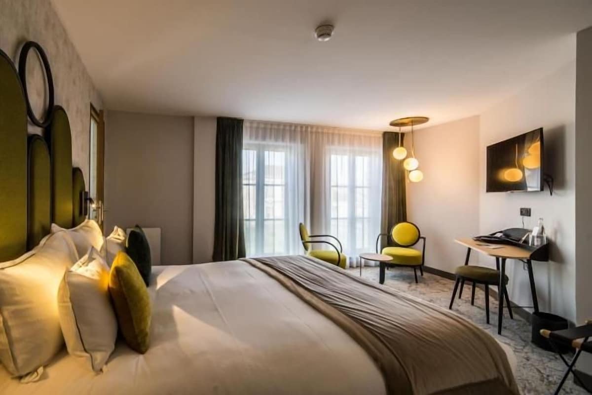 A hotel room with a large bed, a desk, and a chair.