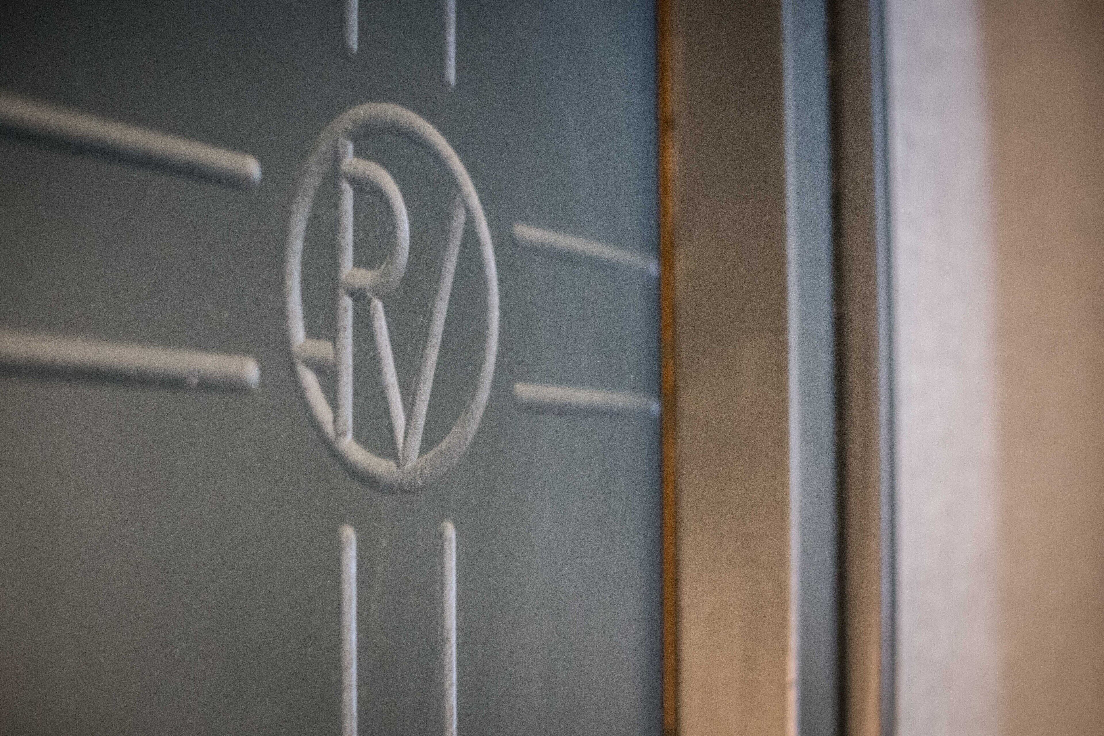 A close-up of a door with a circular emblem featuring a stylized 'R' and 'V' design.