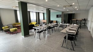 A conference room with multiple tables and chairs, a clock on the wall, and a window with curtains.