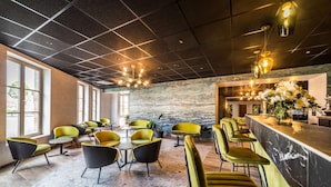 A modern bar area with seating and a stone wall backdrop.