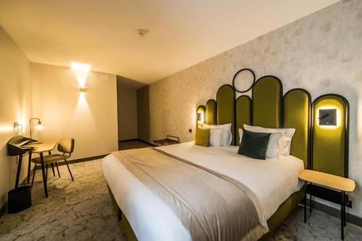 A hotel room with a large bed, a desk, and a chair.
