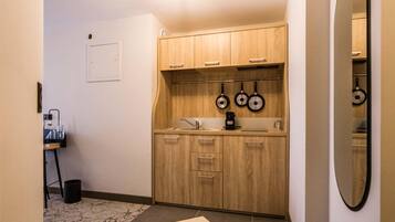 Una cocina compacta con armarios de madera, una cafetera y un colgador para ollas.