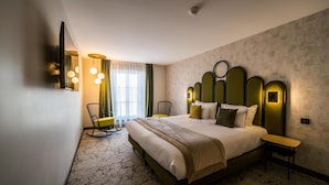 A hotel room with a large bed, a desk, a chair, a TV, and a window with curtains.