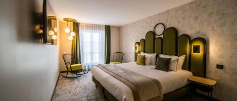 A hotel room with a large bed, a desk, a chair, a TV, and a window with curtains.