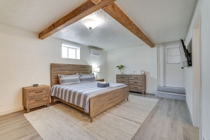 Un dormitorio con cama de madera, mesita de noche, cómoda, ventana y ventilador de techo.