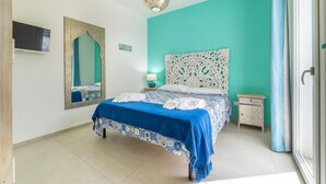 Un dormitorio con una cama, un espejo, una mesita de noche y una lámpara colgante.