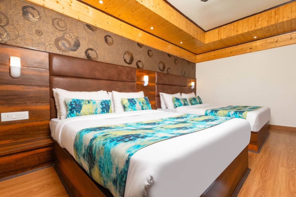 A double bed with a blue and white bedspread, wooden headboard, and wall-mounted lights.