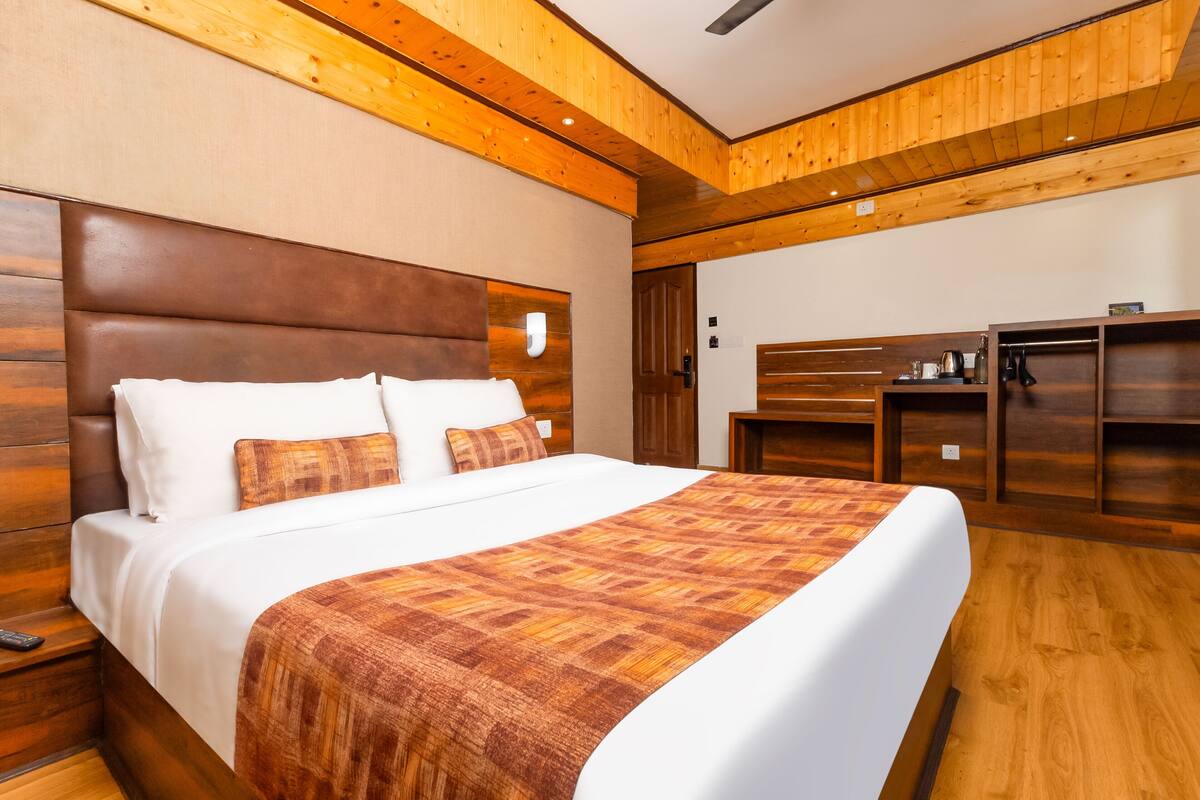 A modern hotel room with a large bed, wooden headboard, and built-in wardrobe.