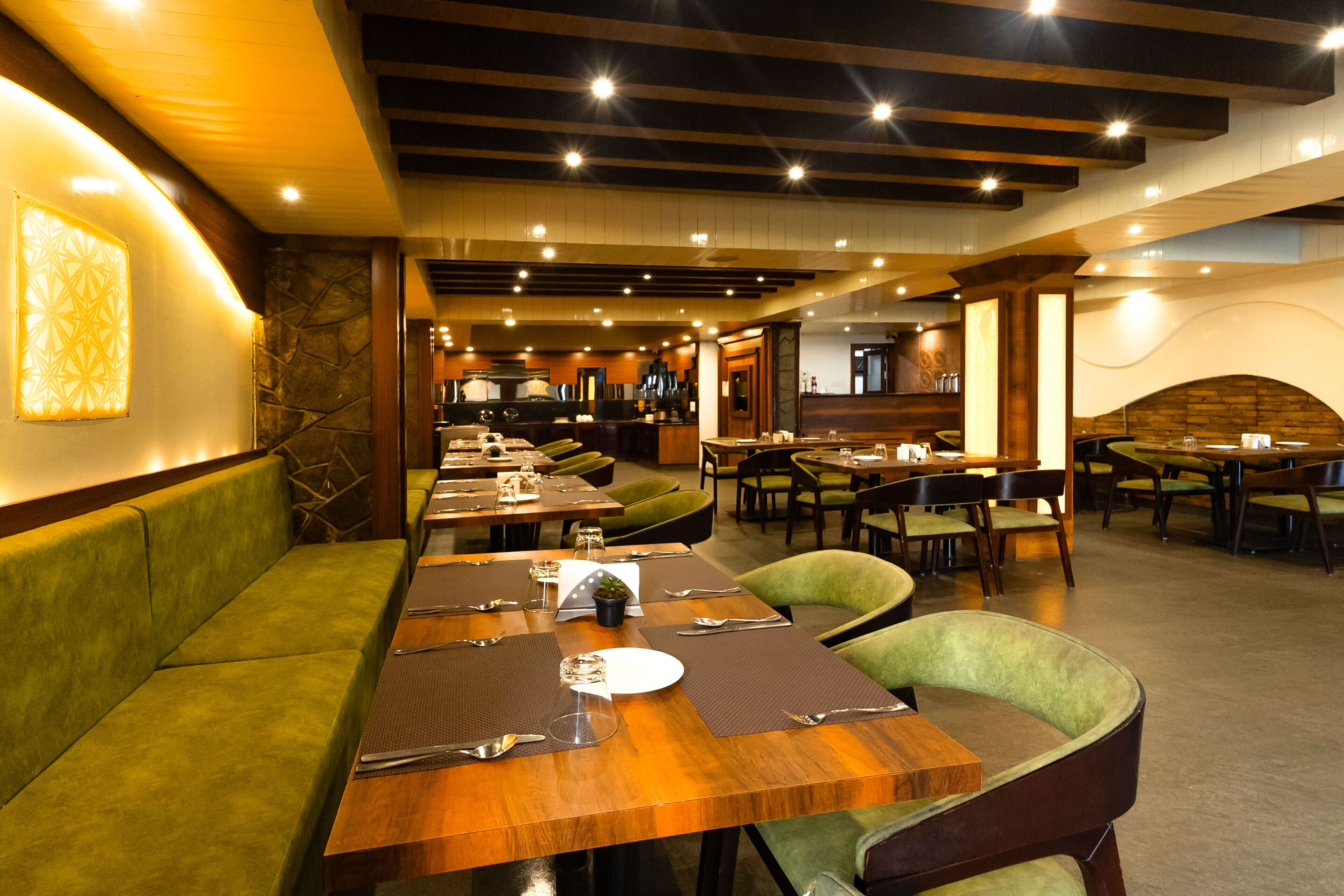 Un restaurant doté de nombreuses tables et de coins repas, de poutres en bois au plafond et d’un mur en pierre.