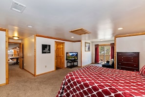 Quarto com cama, televisão, cômoda e janela com cortinas.