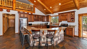 A spacious kitchen with a large island, wooden cabinets, and a stone backsplash.