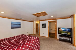 Quarto com cama, televisão e porta que dá para outro cômodo.