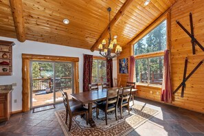 A wooden interior with a dining table, chairs, and a chandelier. - Serenity Now Lodge by Destination Big Bear: Luxury Log Home in Castle Glen Estates! Hot Tub! Pool Table! Ping Pong! (Big Bear Lake)