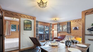 Un intérieur en bois comprenant une table à manger dressée pour quatre personnes, un canapé et un fauteuil.