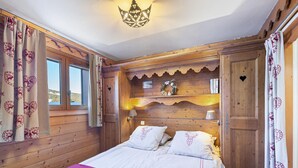 Une pièce en bois avec un lit, des rideaux, un lustre et une fenêtre.