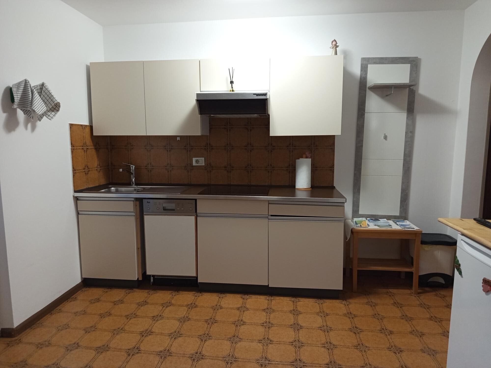 Una cocina compacta con lavavajillas, un fregadero y una pequeña mesa con una revista.