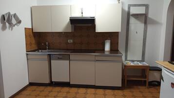Una cocina compacta con lavavajillas, un fregadero y una pequeña mesa con una revista.