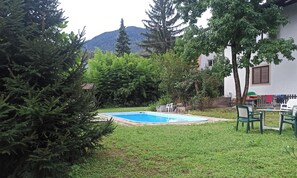 A backyard with a swimming pool, surrounded by trees and a building.