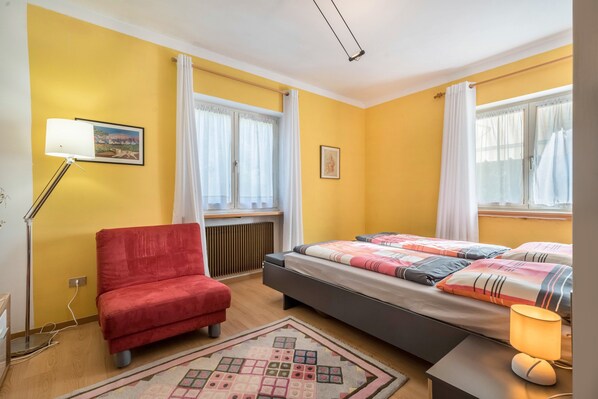 A room with a bed, a red chair, a floor lamp, and a radiator.
