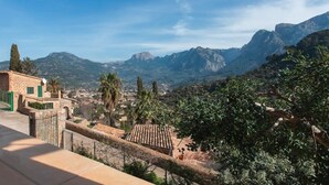Paesaggio montuoso con vista su un edificio con tetto in tegole e muro in pietra.