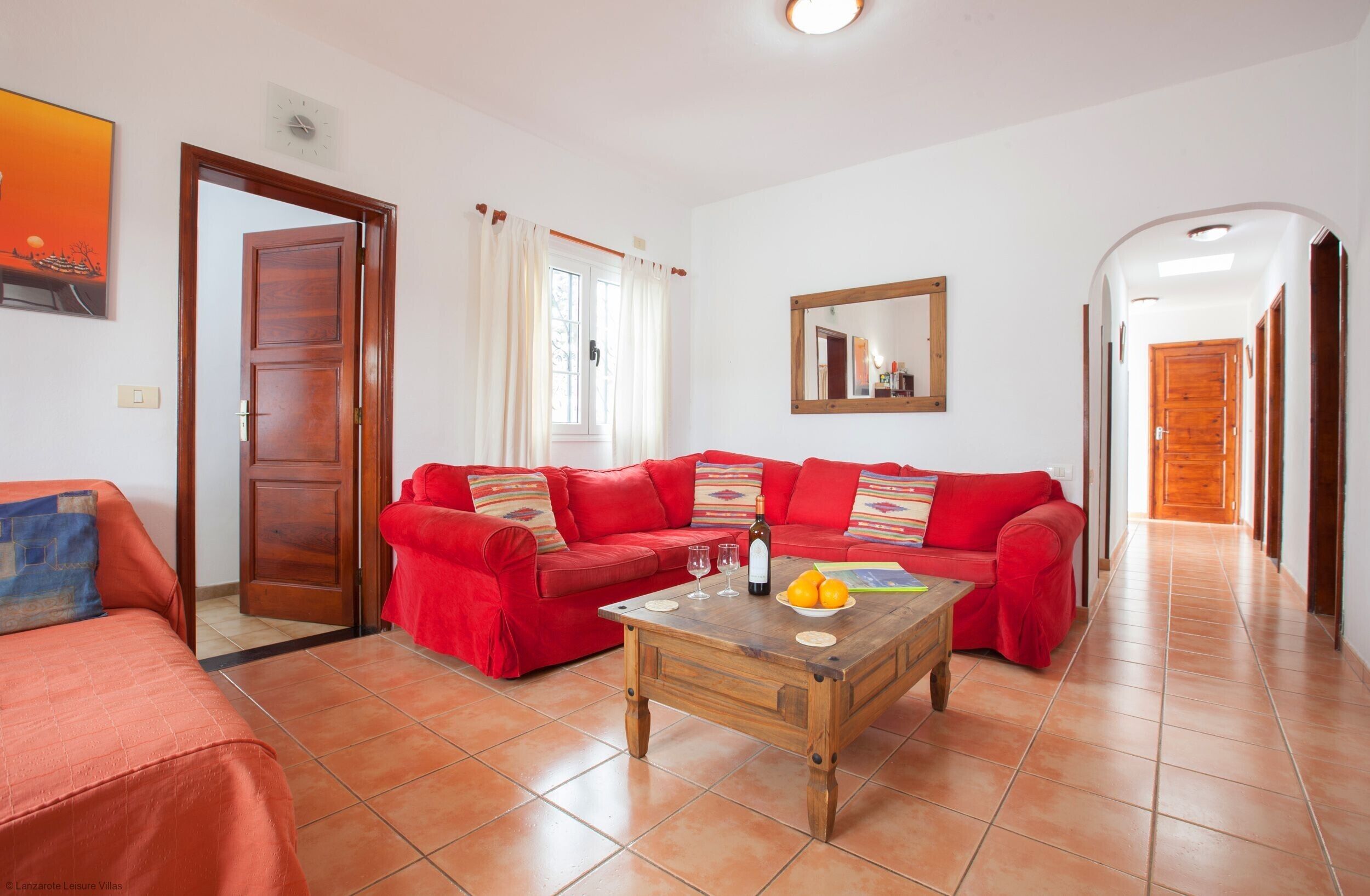 A living room with a red sofa, a wooden coffee table, and a mirror on the wall.