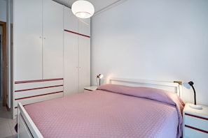 A bedroom with a bed, bedside table, lamp, and wardrobe.
