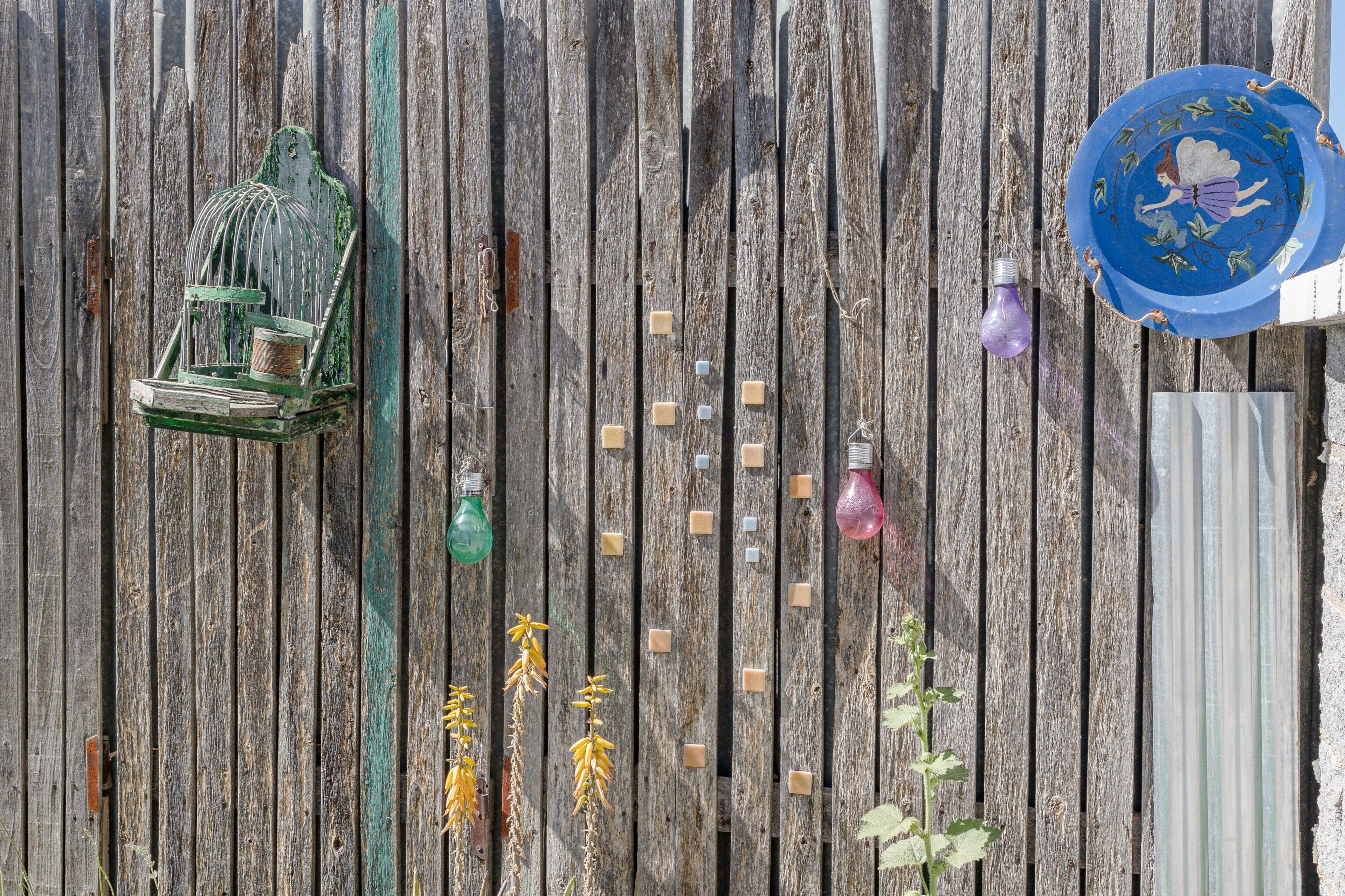 Une clôture en bois, une cage à oiseaux, une assiette décorative et des ampoules.