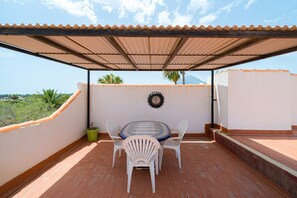 Une terrasse couverte avec une table et des chaises, un mur décoratif et une vue sur le paysage.